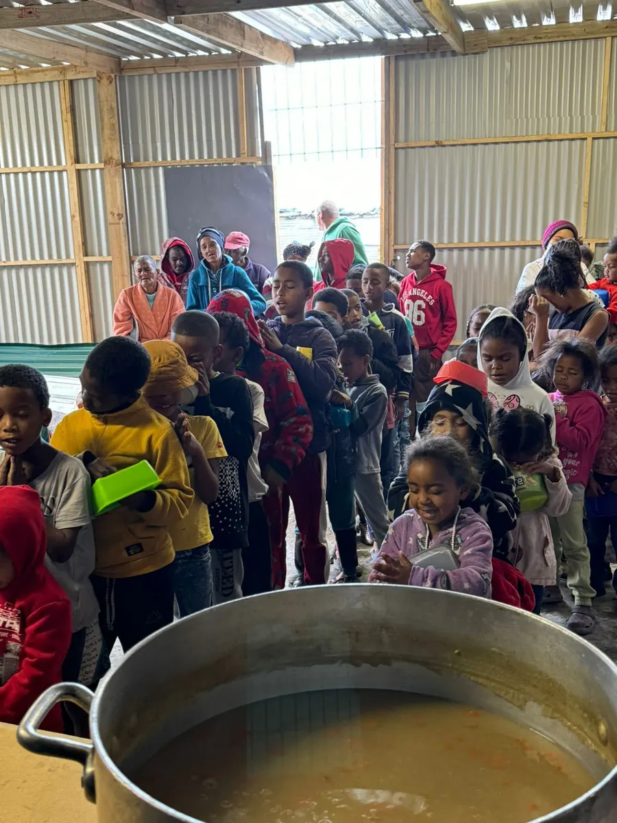 Crianças em fila para receber uma refeição num projeto da Kwakhona na África do Sul